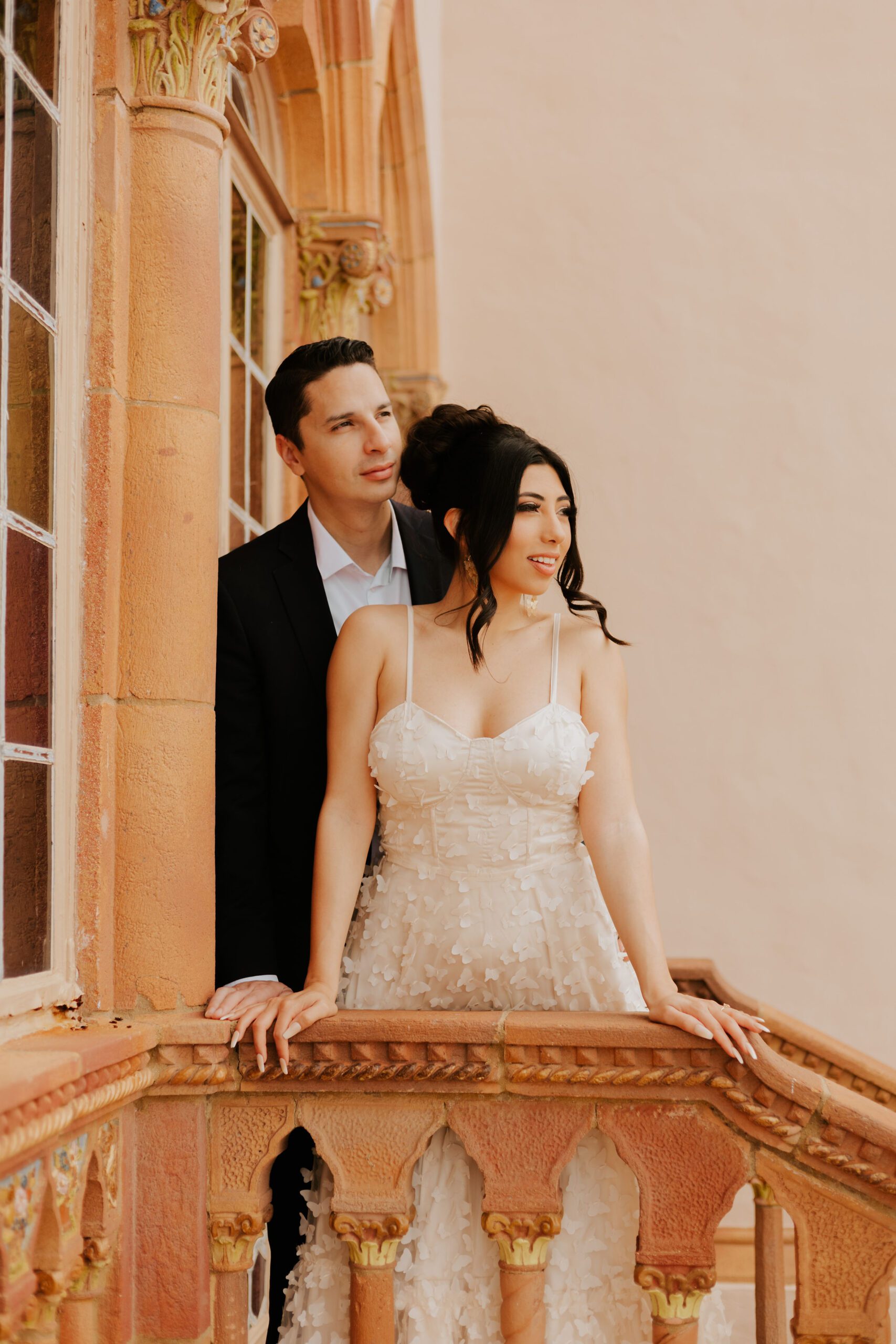Catholic bride and groom stand on staircase looking off into the distance.